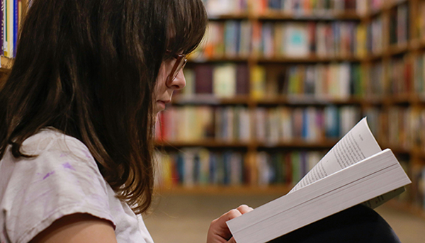 kvinde læser bog på bibliotek